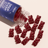 Deep Sleep Dose liegen auf einem hellen Untergrund, mehrere Gummibärchen fallen heraus.